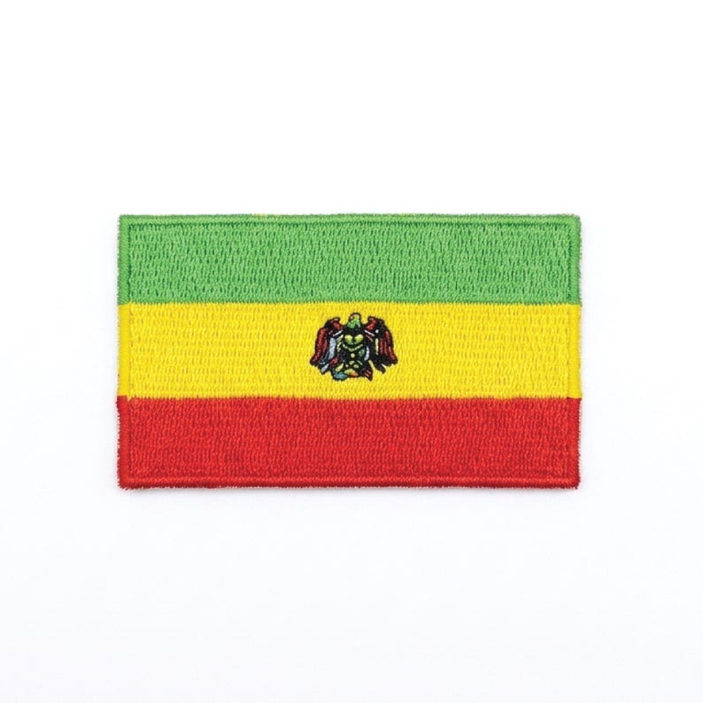 Peut inclure: &Eacute;cusson brod&eacute; repr&eacute;sentant le drapeau de la Bolivie. Le patch rectangulaire pr&eacute;sente des rayures horizontales vertes, jaunes et rouges. Un embl&egrave;me d&eacute;taill&eacute; est centr&eacute; sur la bande jaune. Le patch est destin&eacute; aux v&ecirc;tements ou accessoires.