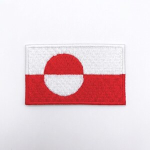 May include: Embroidered rectangular patch featuring the flag of Greenland. The design includes a white upper half and a red lower half, with a large white and red circle offset to the hoist side.
