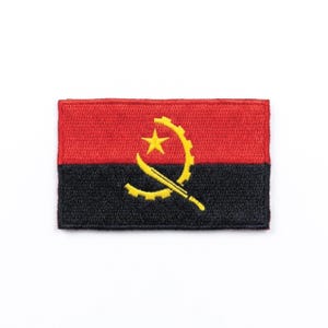 May include: Embroidered patch depicting the flag of Angola. The rectangular patch is divided horizontally, with a red upper section and a black lower section. A yellow emblem, including a star, gear, and machete, is in the centre. Suitable for clothing or accessories.