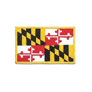 Puede incluir: Un parche rectangular bordado que presenta el diseño de la bandera del estado de Maryland. El patrón consta de cuatro cuadrantes con franjas diagonales alternas en negro y dorado, y símbolos de cruces en rojo y blanco, bordeado por un filo amarillo.