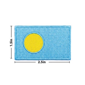 May include: Embroidered patch featuring the flag of Palau. The rectangular patch is light blue with a yellow circle and measures 2.5 inches wide and 1.5 inches high. The flag design is stitched with a light blue border.