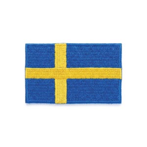 Può includere: Una toppa rettangolare blu con una croce gialla, che ricorda la bandiera svedese. La croce è centrata e ha un aspetto strutturato, in contrasto con lo sfondo blu liscio. È probabile che si tratti di un emblema ricamato.