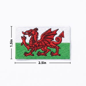 May include: Embroidered patch of the Welsh flag, featuring a red dragon on a white and green background. The patch measures 6.35 cm wide and 3.81 cm high.