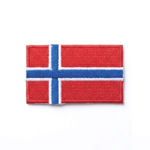 Puede incluir: Un parche bordado rectangular que presenta la bandera de Noruega. El diseño consiste en un fondo rojo con una cruz azul horizontal y vertical delineada en blanco, con la cruz vertical posicionada hacia el lado izquierdo del parche.