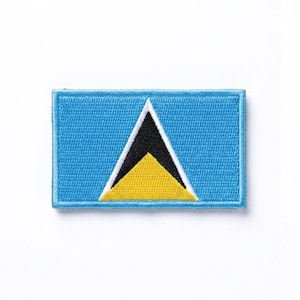 Puede incluir: Un parche rectangular con la bandera de Santa Lucía. El diseño presenta un fondo azul claro, un triángulo negro, un borde blanco y un triángulo amarillo en la base.