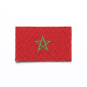 Peut inclure: Un écusson rectangulaire rouge représentant le drapeau du Maroc. L'écusson comporte une étoile verte à cinq branches au centre. L'écusson est en tissu et possède une bordure cousue.
