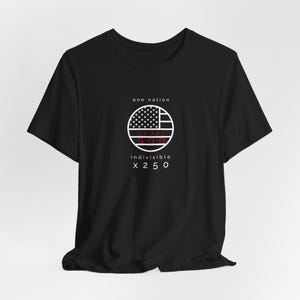 May include: A black short-sleeve t-shirt featuring a white circular graphic on the chest. The graphic contains a stylized American flag, the text "one nation", "under GOD" in red, "indivisible", and the alphanumeric characters "X 2 5 0" below.
