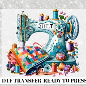 May include: A watercolor illustration of a vintage sewing machine in teal with the word "QUILT" on it. Colorful spools of thread, a quilt, and flowers surround the machine. The text "DTF TRANSFER - READY TO PRESS" is at the bottom.