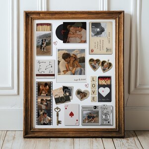 May include: A wooden frame containing a collage of personal items including photographs, a vintage camera, a heart-shaped locket, a metal key, a playing card, matchboxes with custom prints, and wooden letter tiles spelling LOVE on a white background.