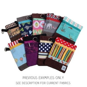 Może przedstawiać: Kolekcja kolorowych torebek z zamkiem błyskawicznym w różnych wzorach, w tym grochy, paski i wzory kwiatowe. Torebki są wykonane z tkaniny i mają brązową lamówkę z weluru. Tekst "PREVIOUS EXAMPLES ONLY" i "SEE DESCRIPTION FOR CURRENT FABRICS" jest wydrukowany pod torebkami.