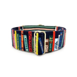 May include: A navy blue dog collar with a colorful pattern of book spines. The collar features a gold metal buckle and is decorated with the titles of classic children's books, including "Treasure Island", "Heidi", and "The Velveteen Rabbit".