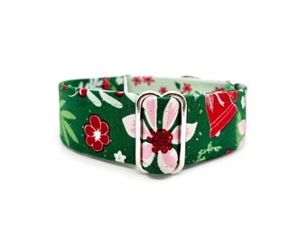 Puede incluir: Un collar verde para perros con un estampado floral con flores rojas y rosas, detalles blancos y una hebilla plateada. El collar es de tela y está diseñado para mascotas.