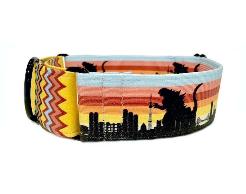 May include: A yellow, red, and blue striped dog collar with a black silhouette of Godzilla destroying a city skyline.