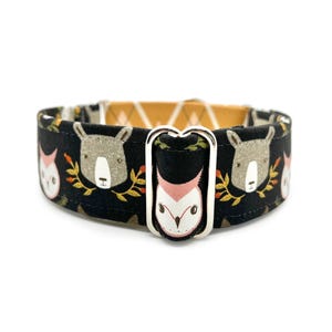 May include: A black dog collar with a repeating pattern of woodland animals, including bears and foxes. The collar has a silver metal buckle and a contrasting yellow and white geometric pattern on the inside.