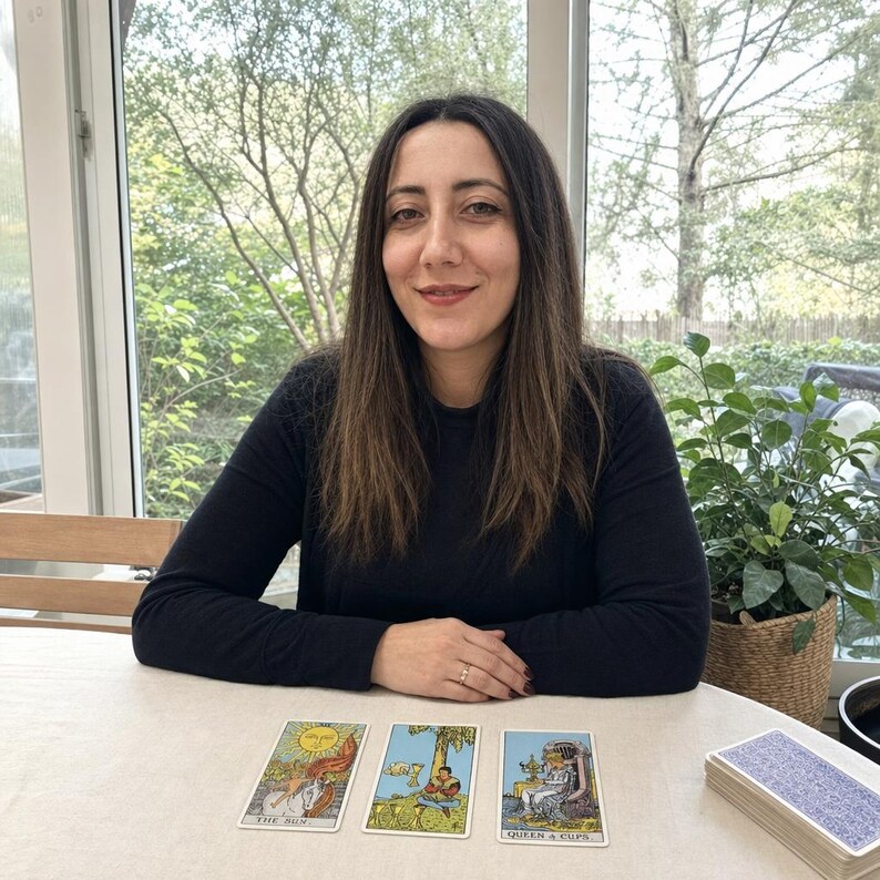 May include: Three tarot cards laid out on a table, featuring The Sun, Four of Cups, and Queen of Cups. The Sun card depicts a child on a white horse, the Four of Cups shows a figure sitting under a tree, and the Queen of Cups shows a seated figure.