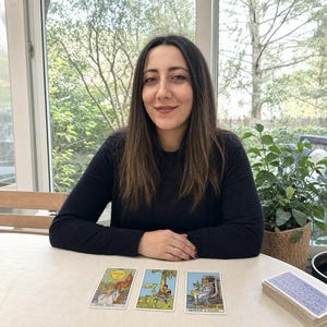 May include: Three tarot cards laid out on a table, featuring The Sun, Four of Cups, and Queen of Cups. The Sun card depicts a child on a white horse, the Four of Cups shows a figure sitting under a tree, and the Queen of Cups shows a seated figure.