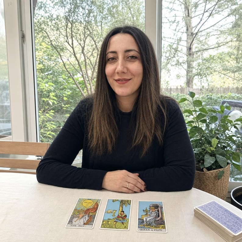May include: Three tarot cards laid out on a table, featuring The Sun, Four of Cups, and Queen of Cups. The Sun card depicts a child on a white horse, the Four of Cups shows a figure sitting under a tree, and the Queen of Cups shows a seated figure.