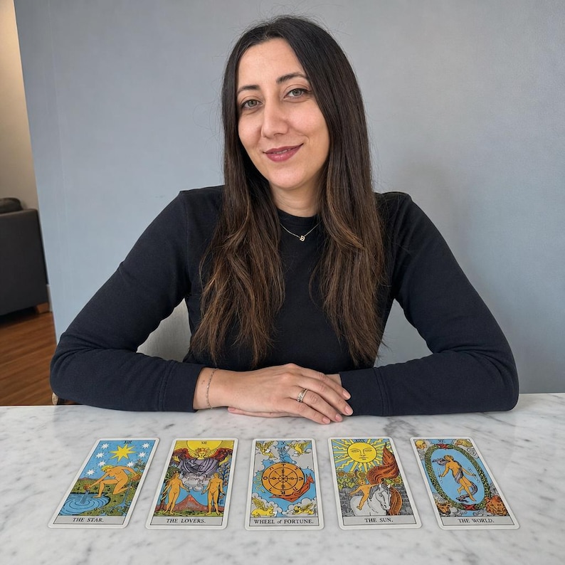 May include: A set of five tarot cards laid out in a horizontal row, featuring The Star, The Lovers, Wheel of Fortune, The Sun, and The World. Each card displays colourful, detailed illustrations with classic imagery and text labels at the bottom.