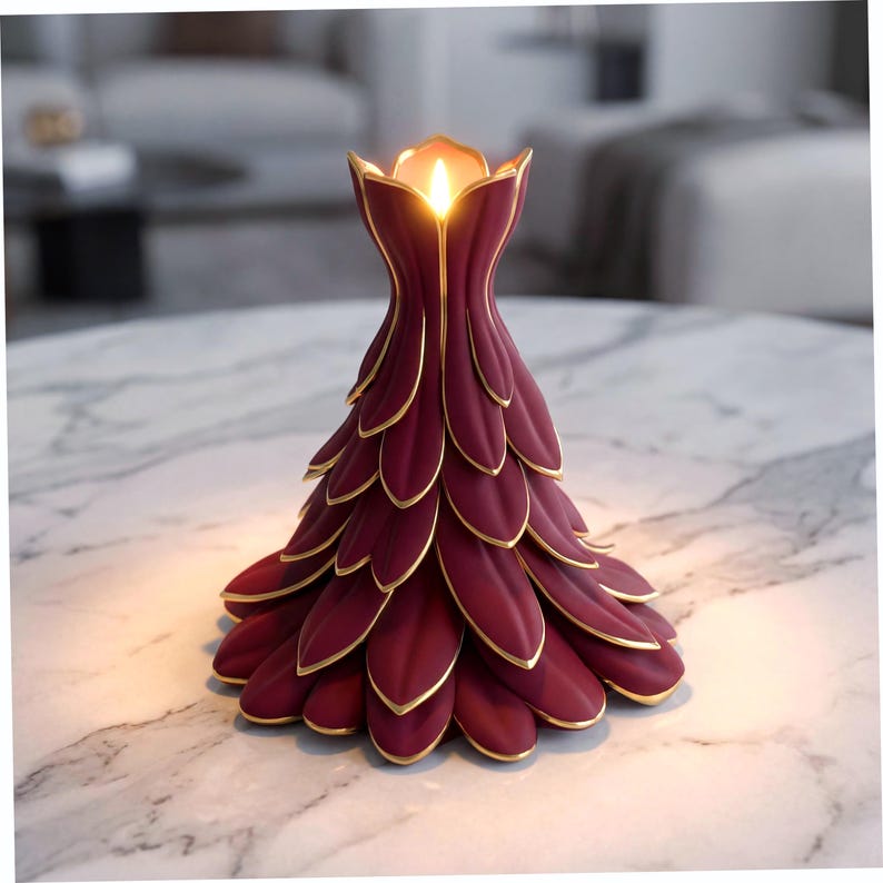 May include: A burgundy candle holder with gold trim, shaped like a stylized flower. The candle holder has a lit candle inside, and is on a marble surface. The design is elegant and decorative.