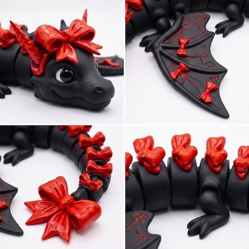 May include: A matte black articulated dragon figurine featuring glossy red bows on its head, wings, and along its segmented tail. The dragon has large black eyes and a smooth finish, with intricate red line details etched onto the surface of its wings.
