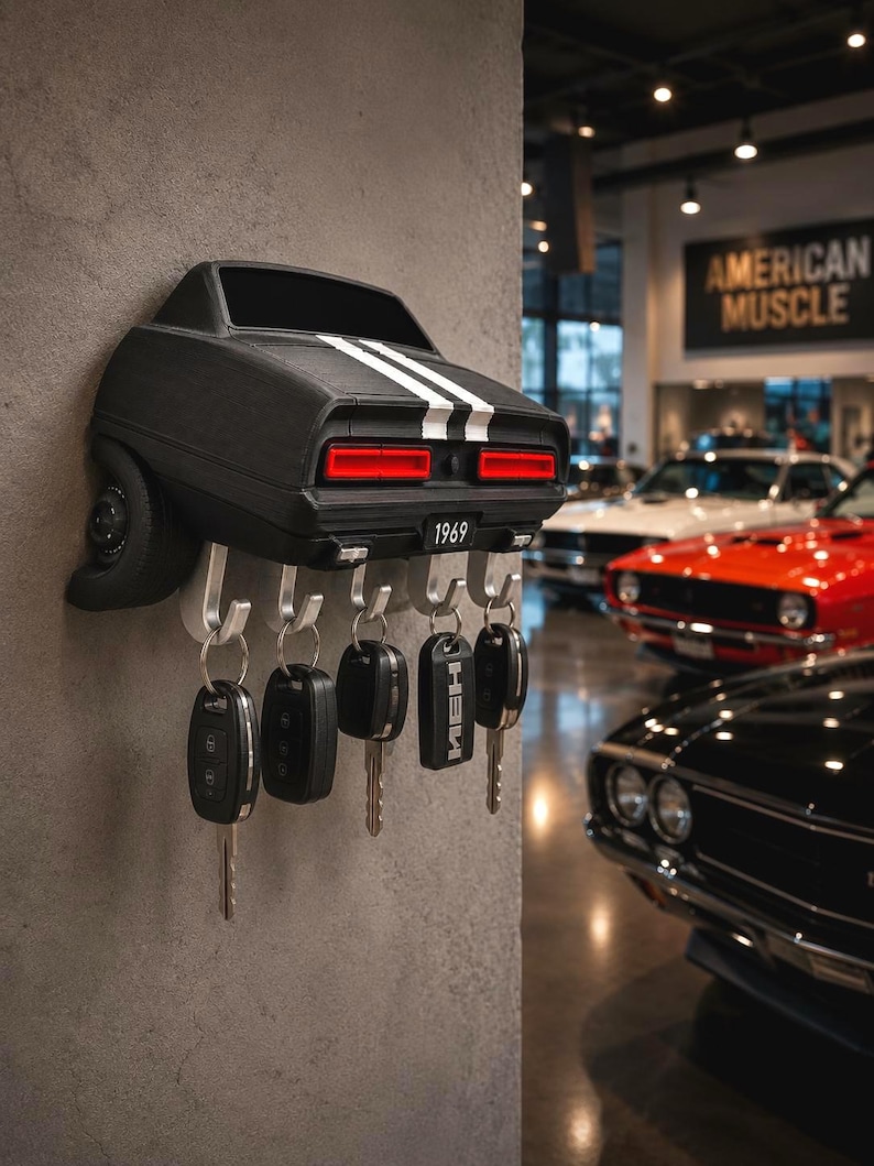May include: A black wall-mounted key holder shaped like the rear of a 1969 muscle car, featuring white racing stripes, red taillights, and a license plate reading 1969. It includes five silver metal hooks, each holding a car key fob.