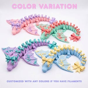 Articulated Bow Dragon available in pink, lavender, black, rainbow, and custom filament colors, compatible with multicolor AMS and manual filament changes.