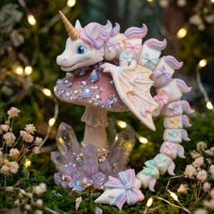 May include: A white unicorn dragon hybrid figurine with pastel pink, blue, and purple hair and bows, featuring a gold horn and wings. The creature rests on a glittery mushroom cap surrounded by purple crystals, showcasing a segmented tail.