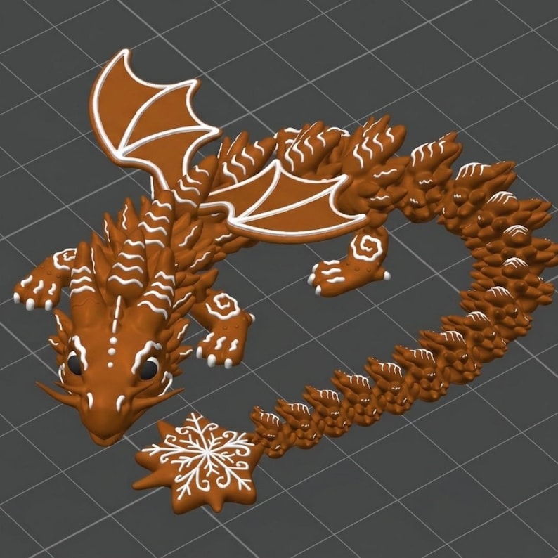 May include: A brown gingerbread dragon figurine featuring white icing details on its wings, back, and head. The dragon has a long, textured tail ending in a star-shaped tip decorated with a white icing snowflake pattern and black eyes.