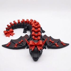 Front view of an articulated Bow Dragon 3D printable model showing an adorable face, oversized head bow, engraved wings, and fully articulated body.