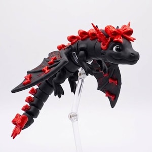 Side profile of a flexible Bow Dragon STL file showing articulated joints, elegant wing details, and decorative bow-themed fantasy design.