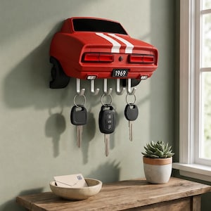 May include: A red wall-mounted key holder shaped like the rear of a 1969 muscle car with white racing stripes, black taillights, and a license plate reading 1969. It features five silver metal hooks holding three sets of car keys.