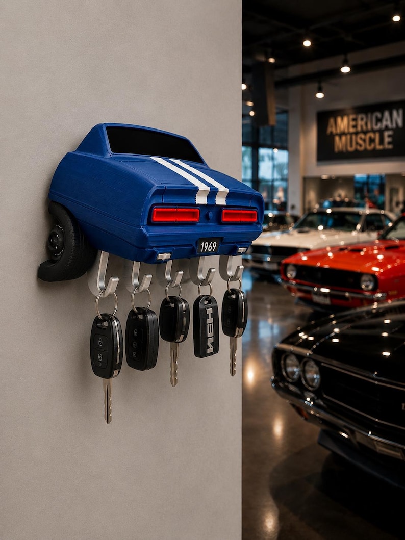 May include: A blue wall-mounted key holder shaped like the rear of a 1969 muscle car, featuring white racing stripes, red taillights, and a number plate reading 1969. Five silver metal hooks extend from the bottom, each holding a set of car keys.