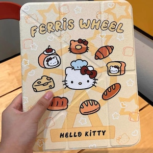Könnte beinhalten: Eine beige Tablet-Hülle mit einem Riesenrad-Design, Hello Kitty und Lebensmittel-Illustrationen. Die Hülle trägt die Aufschrift "FERRIS WHEEL" und "HELLO KITTY". Die Hülle wird von einer Hand gehalten.