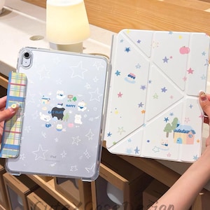 May include: Clear iPad case with a playful design featuring stars and cartoon cats. The case has a transparent back with a colorful pattern. The cover is white with a geometric design and matching illustrations. The text "CAT PLAY HAPPY" is visible.