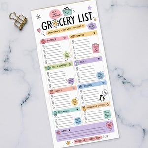 May include: A rectangular grocery list notepad with sections for different food categories. The notepad features the text "GROCERY LIST" and "Shop smart, eat well, live well." It is on a white marble surface, alongside a keyboard and a cup of coffee.