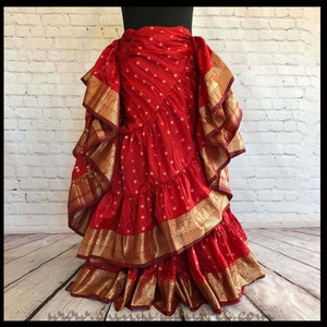 May include: A red and gold skirt with multiple layers of ruffles. The skirt is made from a patterned fabric with gold accents.