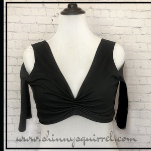 Peut inclure: Top noir à épaules dénudées avec un décolleté en V profond et un détail plissé à l'avant. Le haut a des manches courtes et est fait d'un tissu doux et extensible.