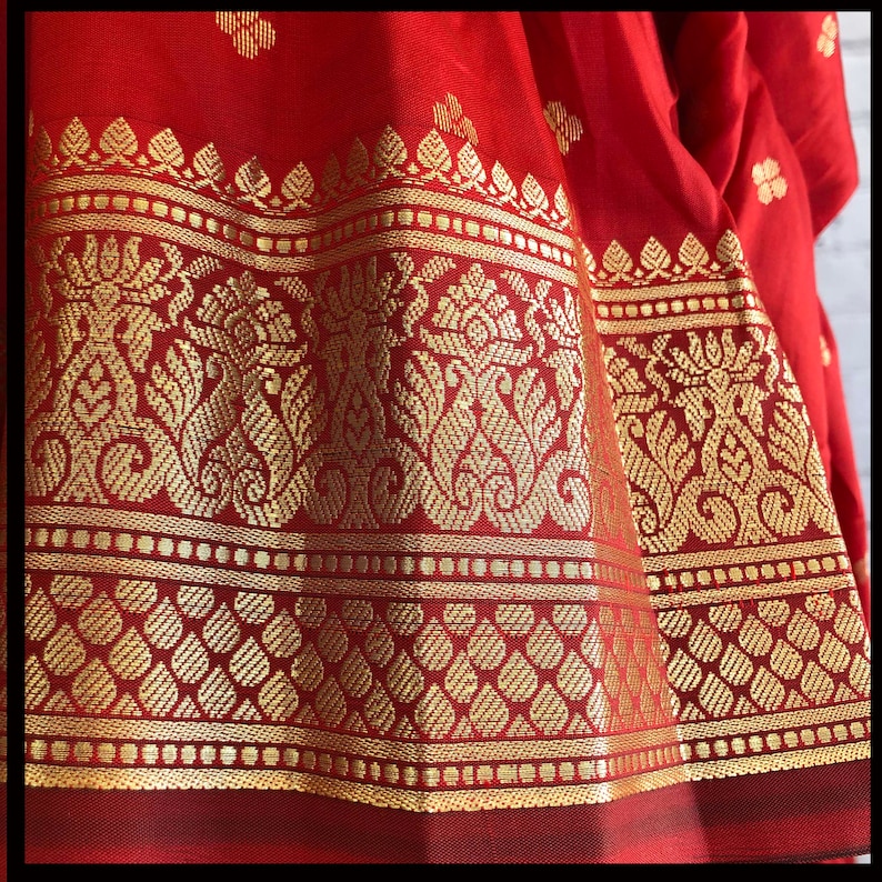 May include: Red silk fabric with a gold border featuring intricate floral patterns. The border has a repeating design of small gold dots.