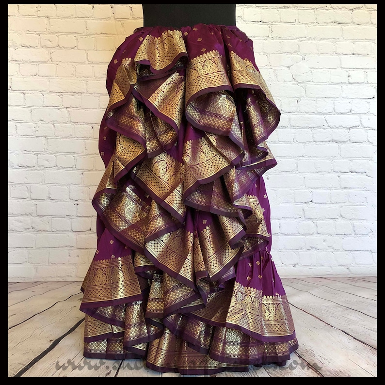 May include: A purple skirt with gold trim and multiple layers of ruffles. The skirt is made of a soft, flowing fabric and has a vintage look.