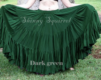 May include: A dark green, multi-layered, cotton skirt with a gathered waist. The skirt is full and flowing, with many ruffles. The text "Shiny Squirrel" is written in cursive on the skirt.