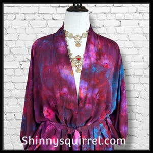 Könnte beinhalten: Ein Batik-Robe in Lila-, Rot- und Blautönen mit passendem Gürtel. Die Robe wird auf einer Schaufensterpuppe mit einer silbernen Halskette präsentiert. Der Text "Shinnysquirrel.com" ist unten sichtbar.