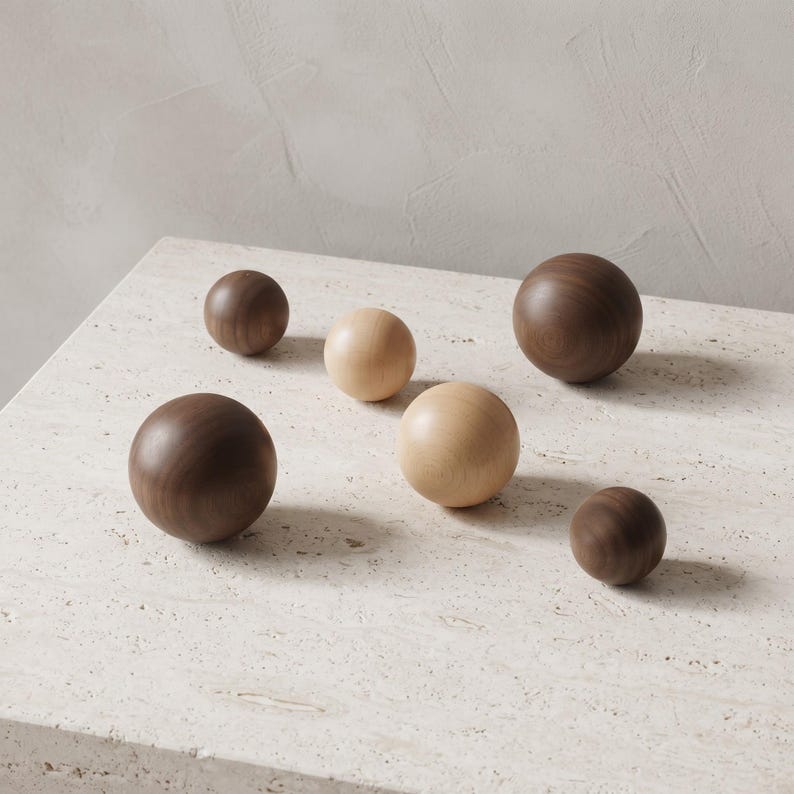 May include: A collection of six smooth, spherical wooden objects of varying sizes. Three spheres are crafted from a dark brown wood, while the other three are made from a lighter, pale beige wood. Each sphere features a visible natural wood grain.
