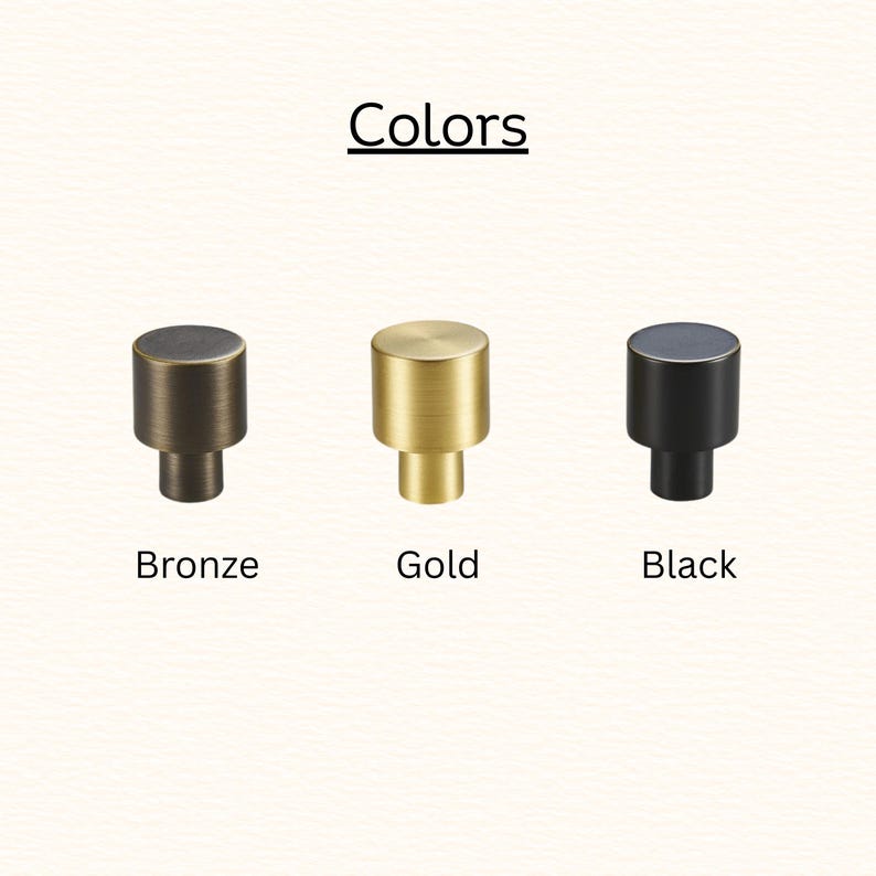 May include: Three cylindrical cabinet knobs arranged in a row, labeled with the text Colors above and the labels Bronze, Gold, and Black below each respective knob. The knobs feature a smooth, solid finish in metallic bronze, gold, and matte black.