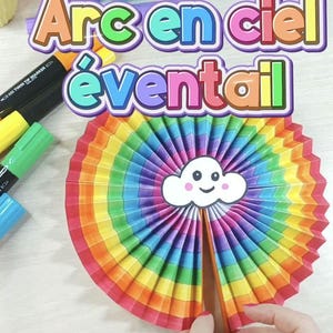 May include: A vibrant rainbow-coloured paper fan with a smiling cloud at its centre. The fan is made of pleated paper in a spectrum of colours. The text "Arc en ciel éventail" is displayed above the fan.