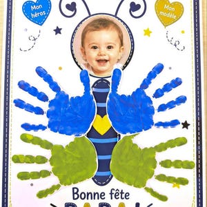 Peut inclure: Une affiche rectangulaire avec une photo centrale d'un bébé souriant encadré en abeille. Le design inclut des ailes en empreintes de mains bleues et vertes, des étoiles jaunes et bleues, des cœurs avec Mon héros et Mon modèle, et Bonne fête PAPA!