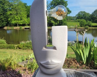 Lampada a sospensione con scultura astratta a forma di volto, realizzata in cemento cellulare. Pezzo di design moderno, unico e artigianale.