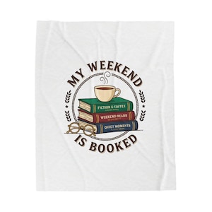 May include: White throw blanket with a printed design. The design includes a stack of books, a coffee cup, and spectacles within a circular frame. The text reads "MY WEEKEND IS BOOKED". The books are labelled "FICTION & COFFEE", "WEEKEND READS", and "QUIET MOMENTS".