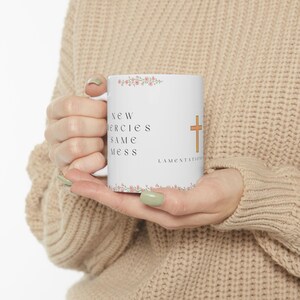 May include: White ceramic mug with the text "New Mercies Same Mess" and a gold cross. The mug is decorated with pink floral accents and the word "Lamentations".