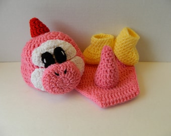 May include: A handmade crochet baby set in pink, white, red, and yellow. The set includes a hat with a red horn, white accents, and black eyes, along with a pair of yellow booties and a pink horn.