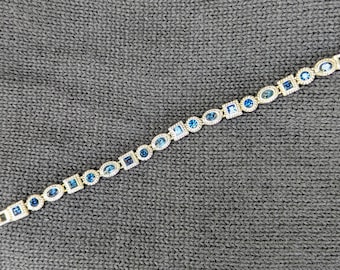 Pulsera de cristal azul con detalles de cuerda plateada.